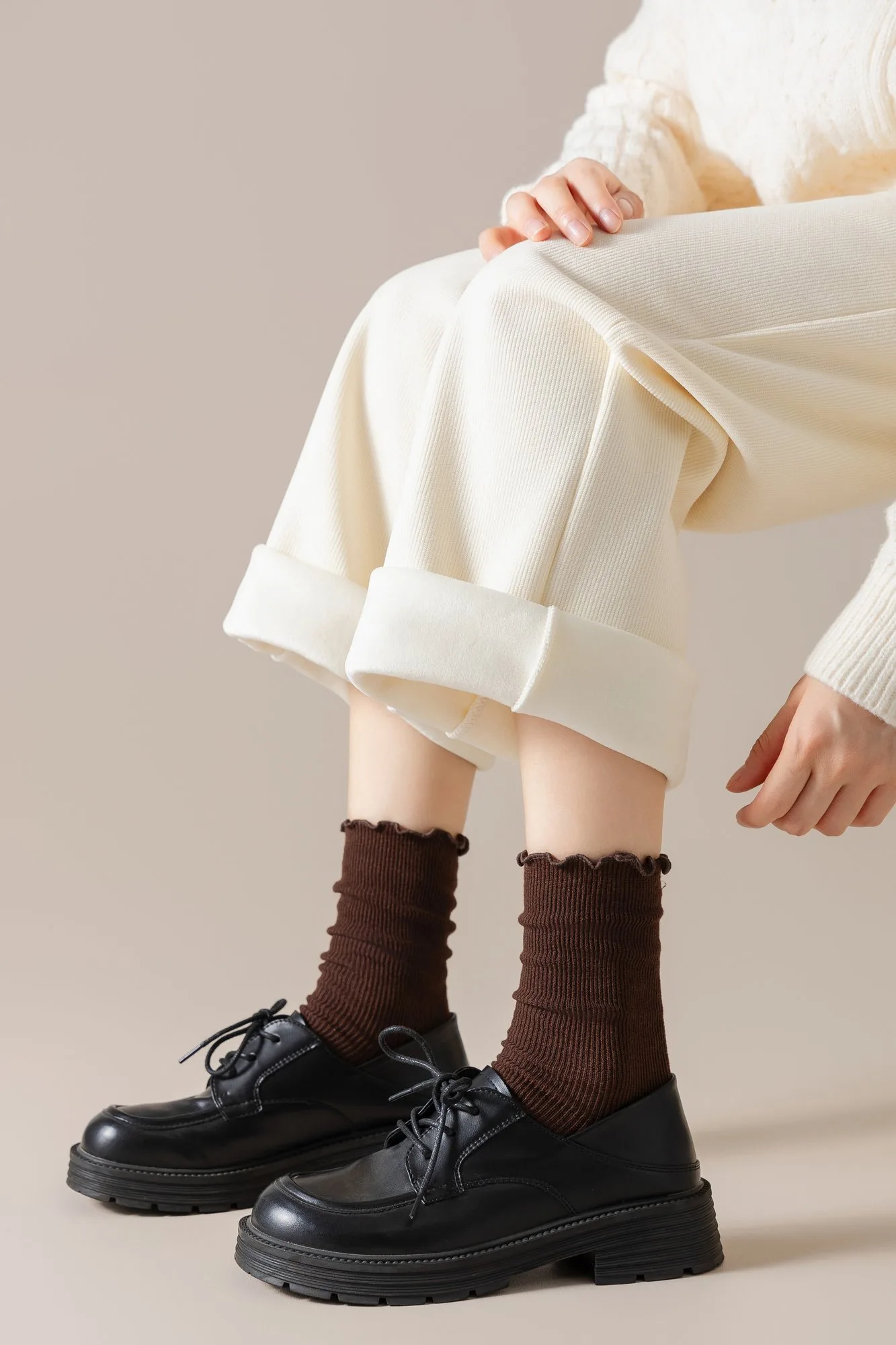 Ruffle-edge slouch crew socks worn with lace-up shoes, styled under rolled-up trousers.