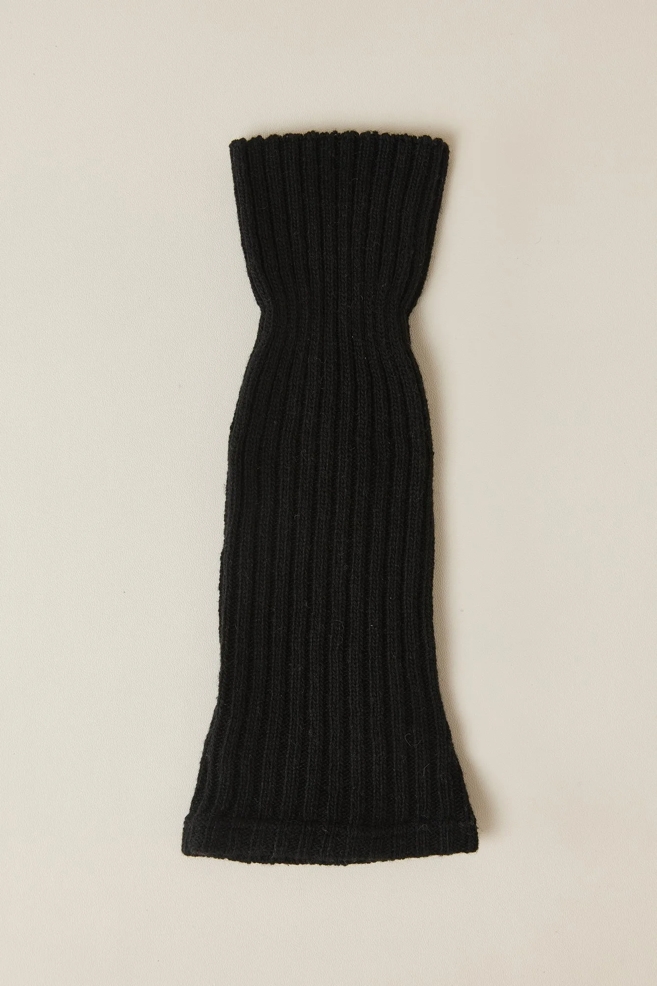 A single ribbed slouch leg warmer laid flat, showing the open footless tube shape, ribbed top and ribbed bottom band.
