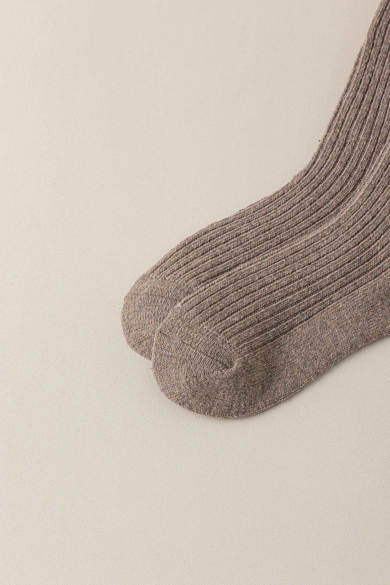 Close-up of the toe and heel of a wool-blend ribbed knee-high sock, showing the yarn and stitch structure.